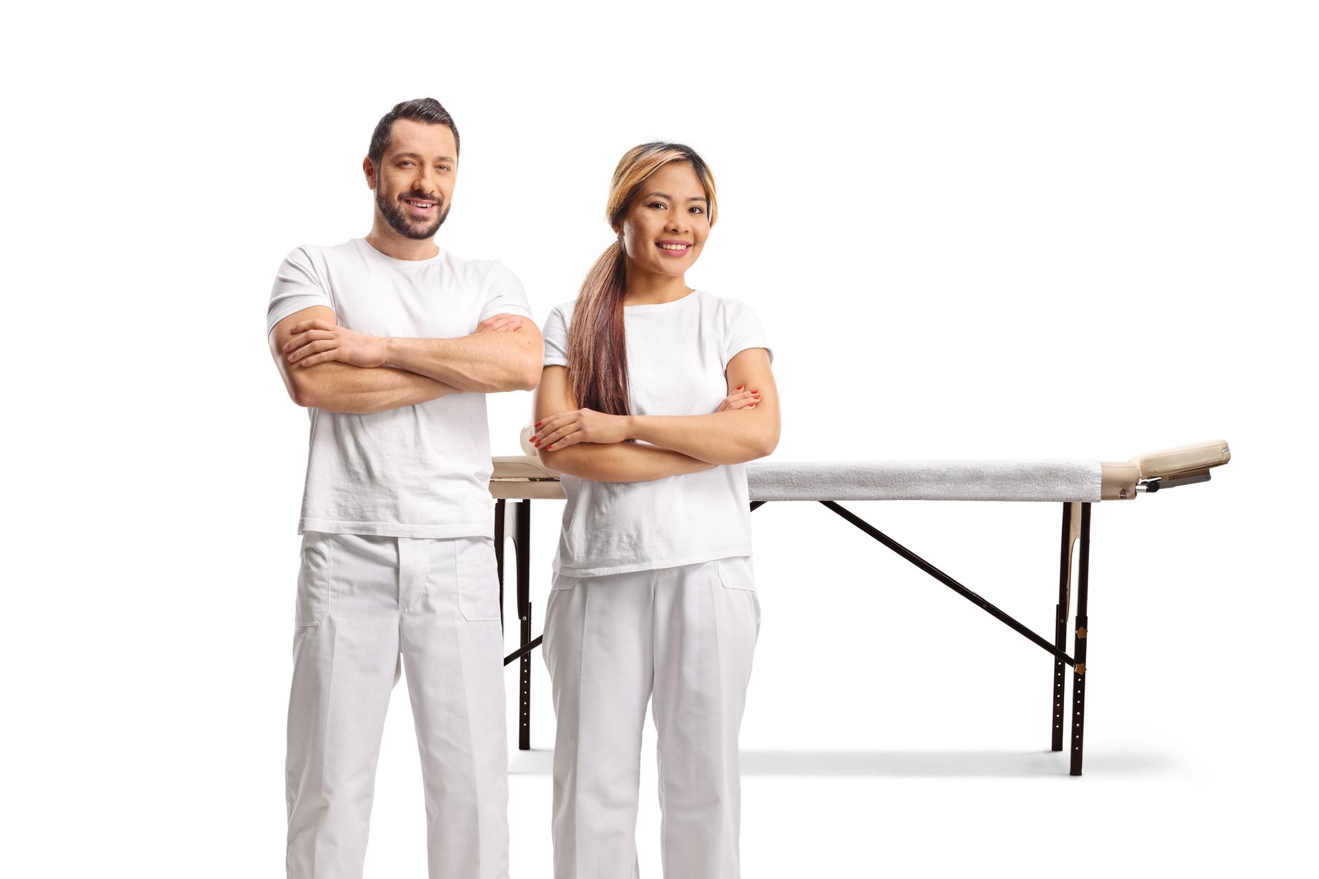 Male and female massage therapists in front of a massage table