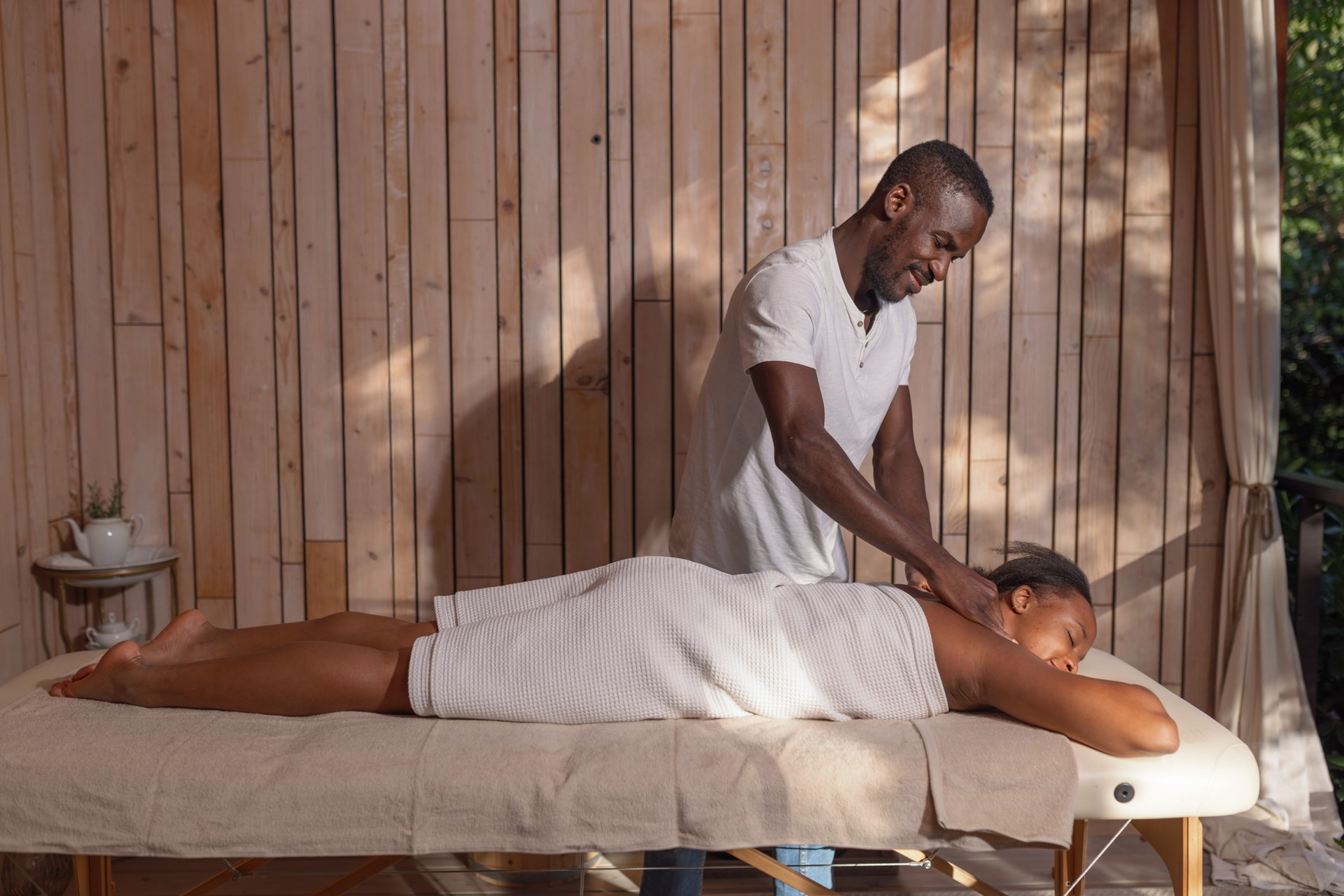 Professional African American masseur providing a relaxing massage to a female client
